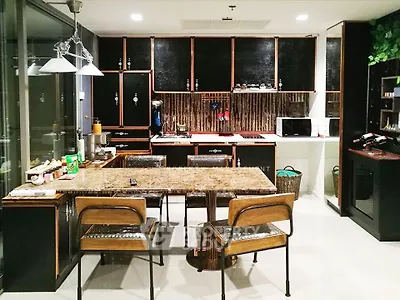 Modern kitchen with sleek black cabinets and marble dining table, featuring open layout and contemporary design.