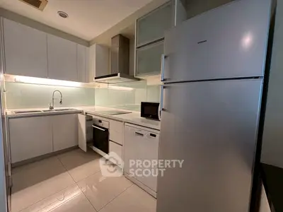 Modern kitchen with sleek white cabinets, built-in appliances, and glossy tile flooring.