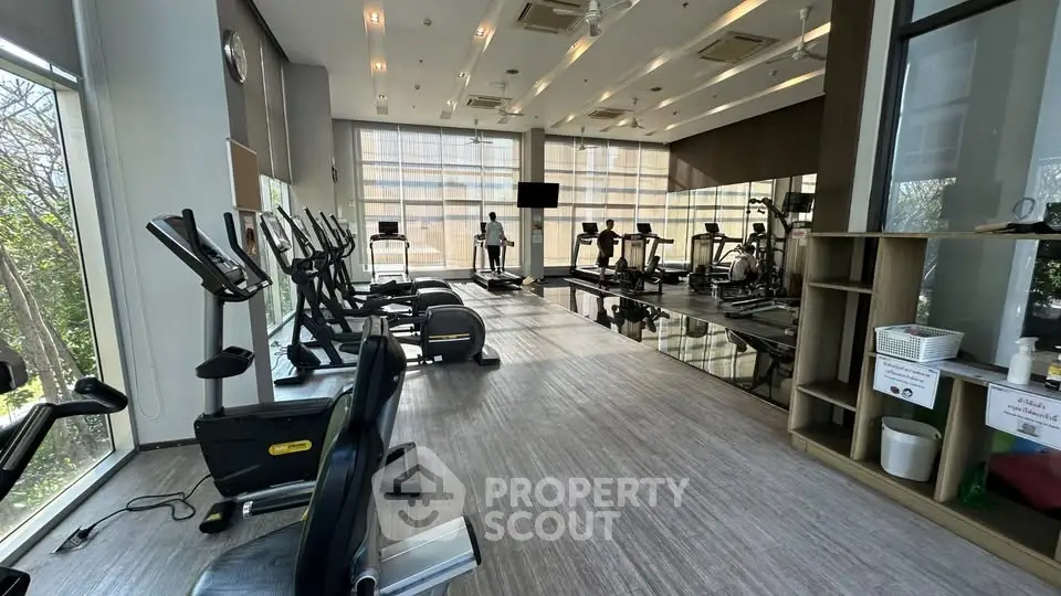 Spacious modern gym with state-of-the-art equipment and large windows for natural light.