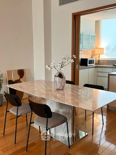 Elegant dining area with marble table and modern kitchen in open layout apartment.