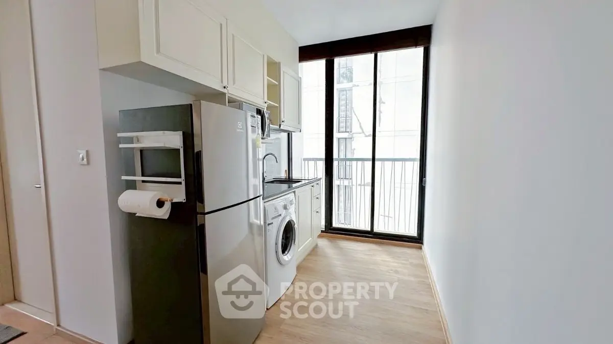 Modern kitchen with washing machine and large window for natural light.