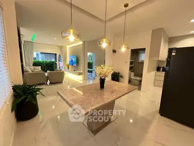 Modern open-plan living and dining area with elegant lighting and marble table.