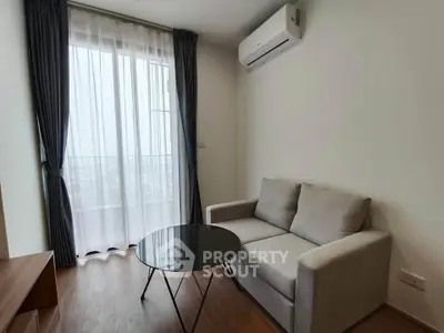 Modern living room with sleek sofa, glass coffee table, and large window with city view.