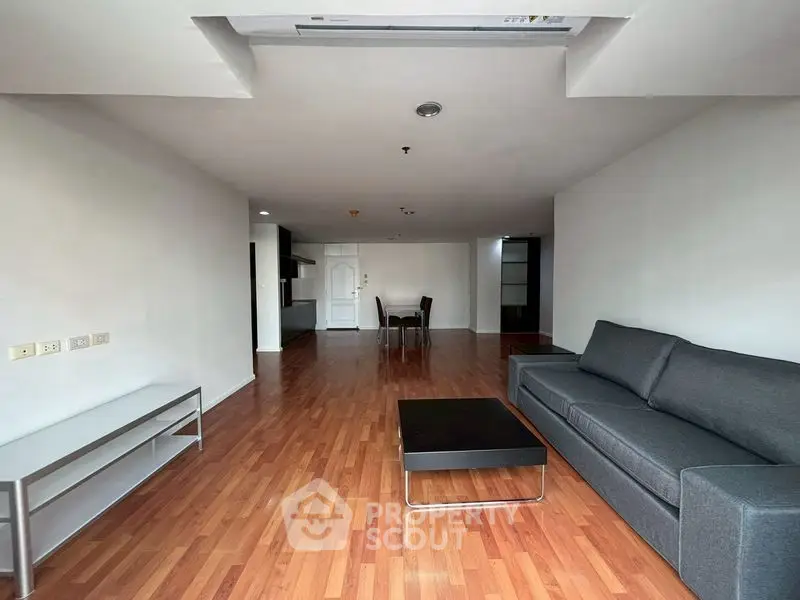 Spacious modern living room with wooden flooring and sleek furniture in a contemporary apartment.