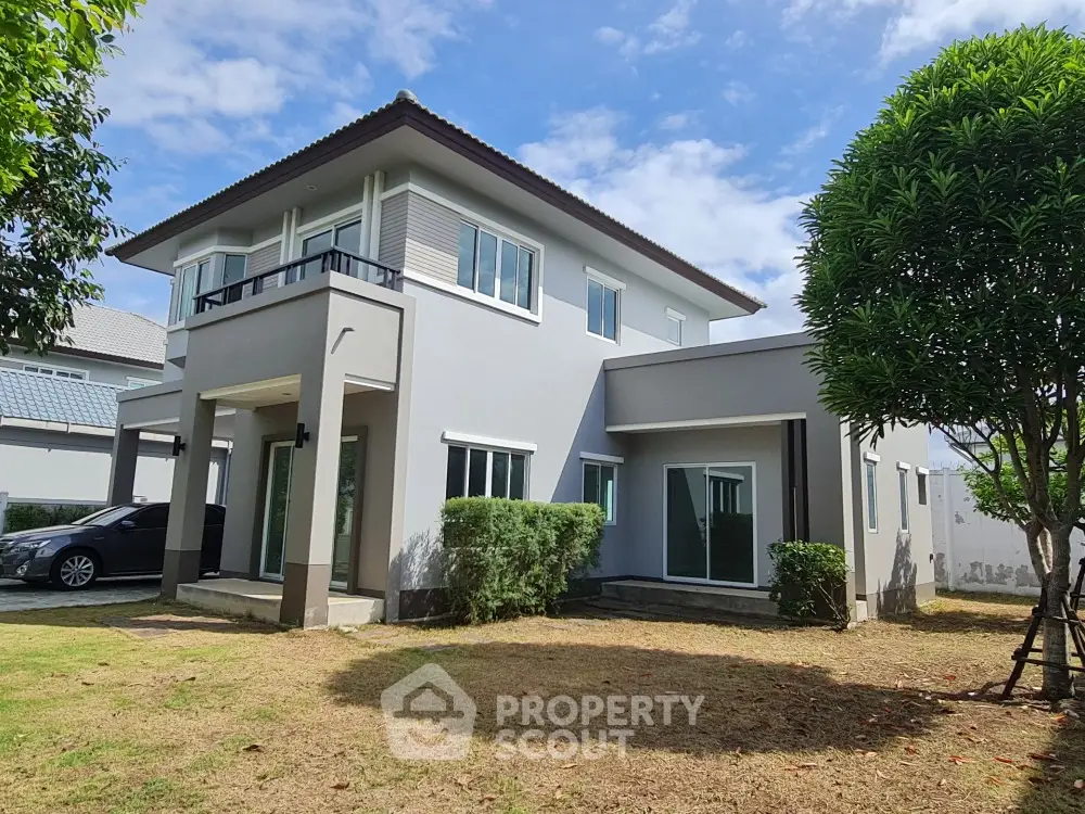 Modern two-story house with lush garden and carport in a serene neighborhood.