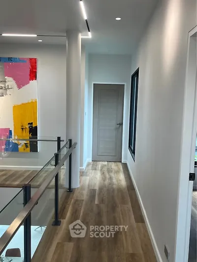 Modern hallway with wooden flooring and contemporary art in a stylish home interior.