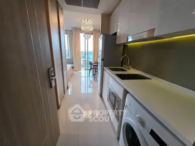 Modern apartment kitchen with sleek appliances and open layout leading to a bright living area.