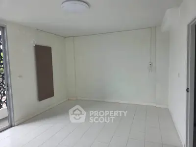 Spacious empty room with white tiled floor and balcony access, ideal for customization.