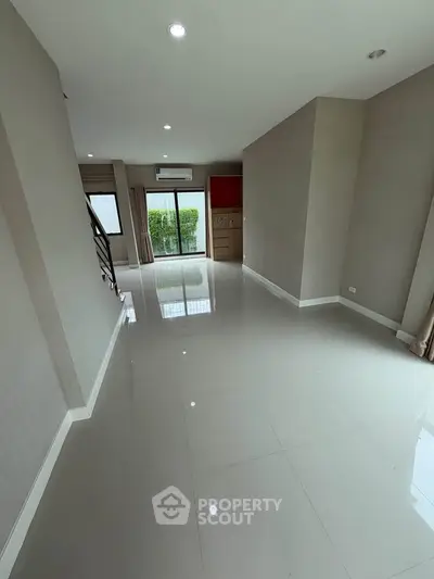 Spacious modern living room with glossy tile flooring and large windows for natural light.
