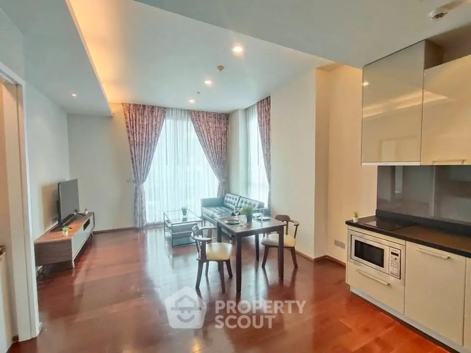 Modern living room with open kitchen, hardwood floors, and stylish furniture