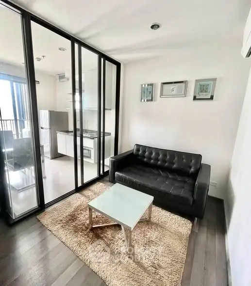Modern living room with glass partition and sleek black sofa in a cozy apartment.