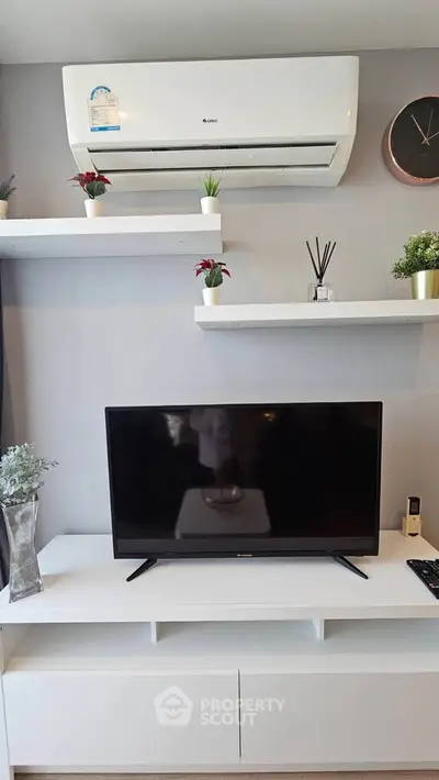 Modern living room with sleek TV setup and stylish shelves, featuring air conditioning and minimalist decor.