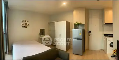 Modern studio apartment with open layout, featuring a cozy bed, compact kitchen, and washing machine.
