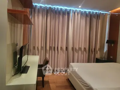 Modern bedroom with sleek design, featuring a large bed, flat-screen TV, and elegant curtains.