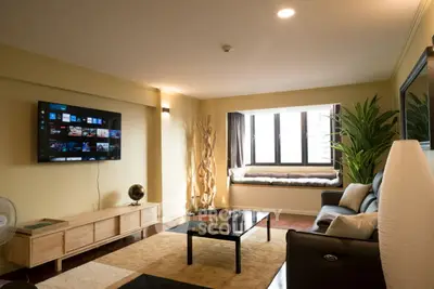 Stylish living room with modern decor, large TV, and cozy seating area by the window.