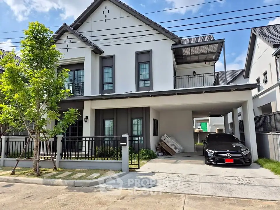 Modern two-story house with carport and luxury car in driveway, featuring sleek design and spacious layout.