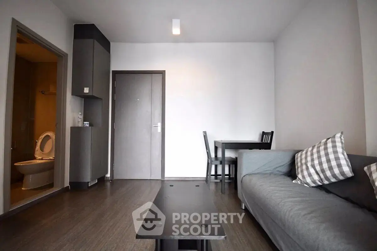 Modern living room with sleek furniture and open layout, adjacent to a compact bathroom.