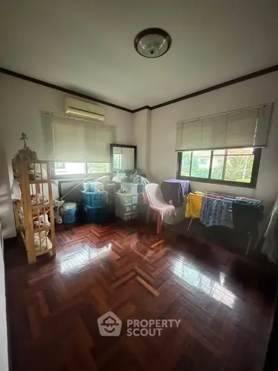 Spacious room with wooden flooring and large windows, ideal for storage or creative space.
