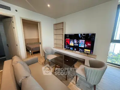 Modern living room with stylish furniture and large TV, adjacent to a cozy bedroom.