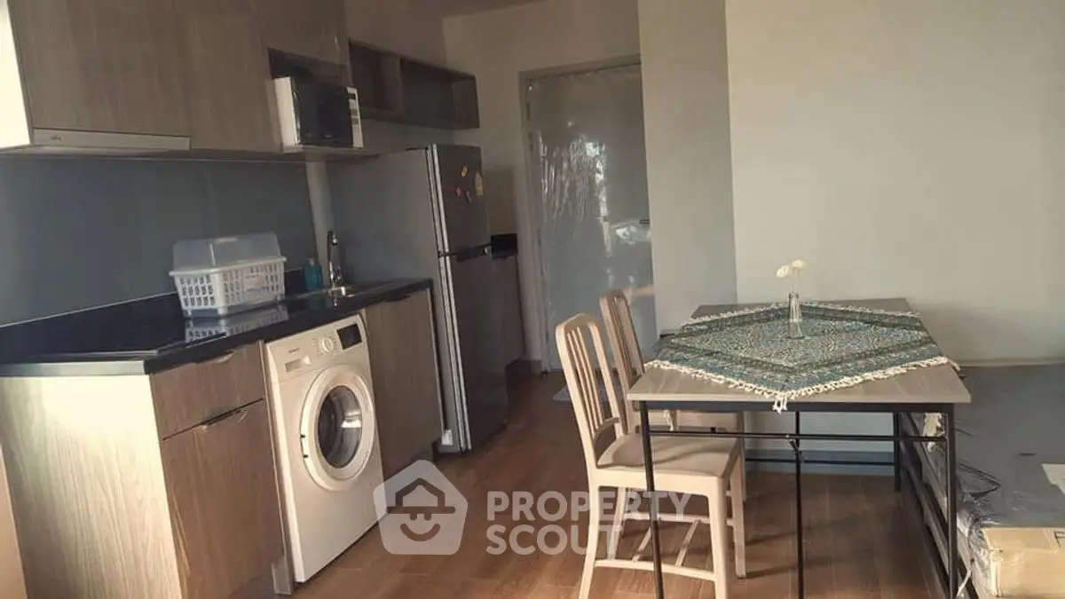 Modern kitchen with washing machine and dining area in cozy apartment.