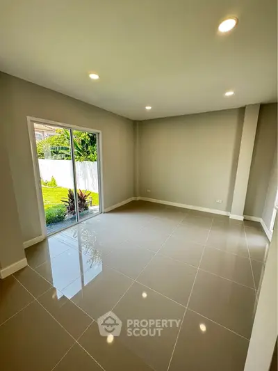 Spacious modern living room with large windows and garden view, perfect for natural light lovers.