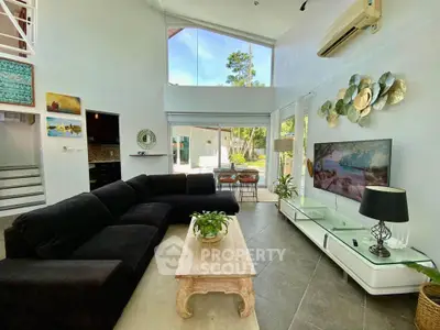 Spacious modern living room with high ceilings and large windows offering natural light and garden view.