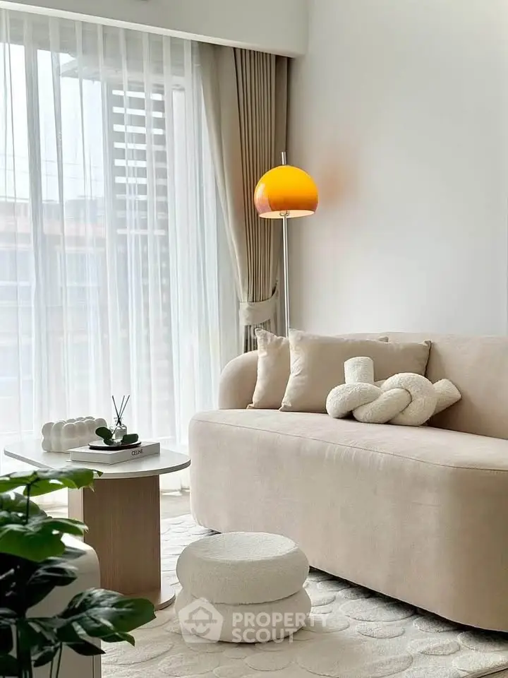 Elegant living room with modern beige sofa, stylish lamp, and floor-to-ceiling windows for natural light.