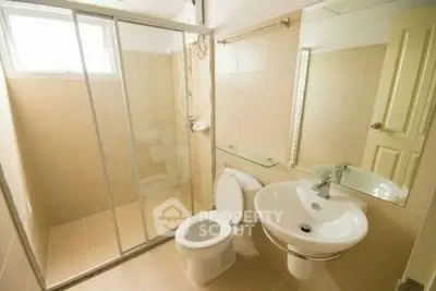 Modern bathroom with glass shower and sleek fixtures in a bright, tiled space.