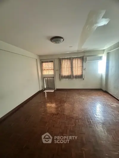Spacious empty room with wooden flooring and natural light, ideal for customization.