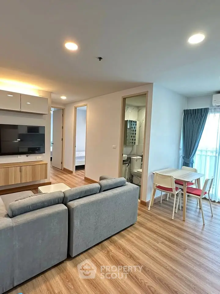 Modern living room with cozy sofa, dining area, and view into bedroom, featuring stylish decor and natural light.