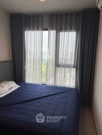 Cozy bedroom with large window offering stunning city view, perfect for relaxation and comfort.