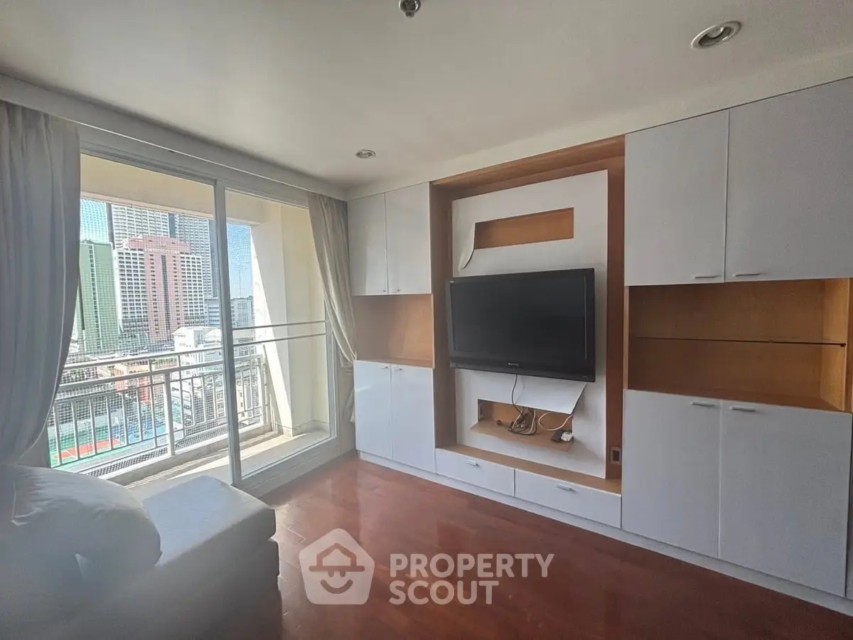 Spacious living room with built-in TV unit and balcony view in modern apartment