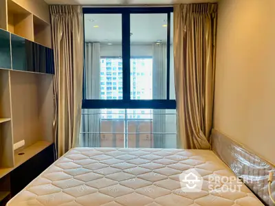 Modern bedroom with large window and city view, featuring elegant curtains and built-in shelving.