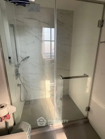 Modern bathroom with glass shower enclosure and marble tiles