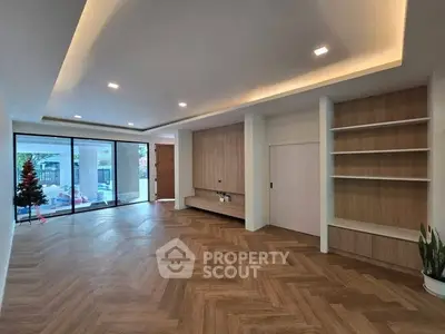Spacious modern living room with wooden flooring and built-in shelves, perfect for stylish living.