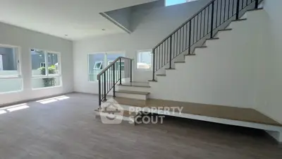 Spacious modern living room with elegant staircase and large windows