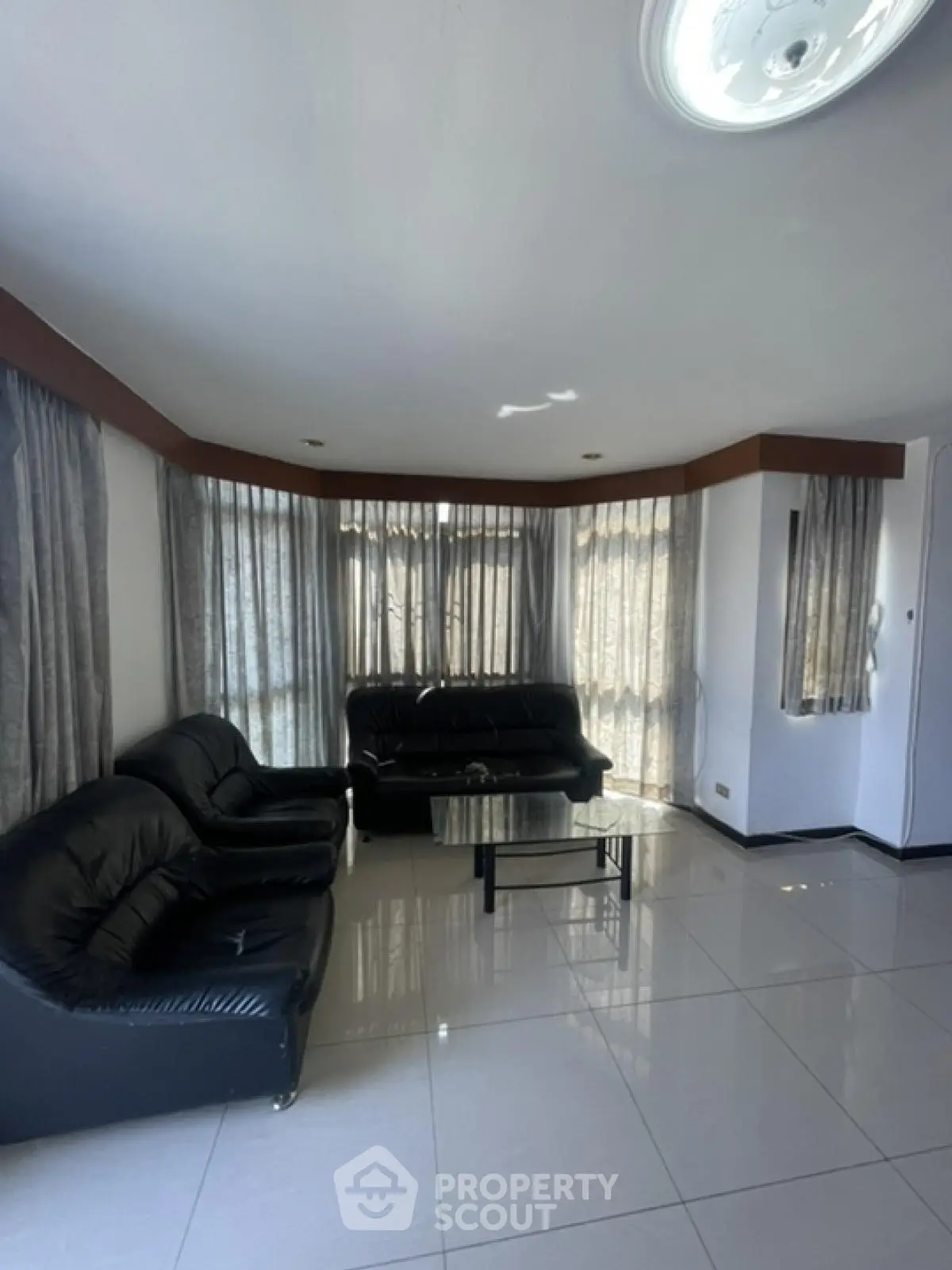 Spacious living room with modern black leather sofas and large windows