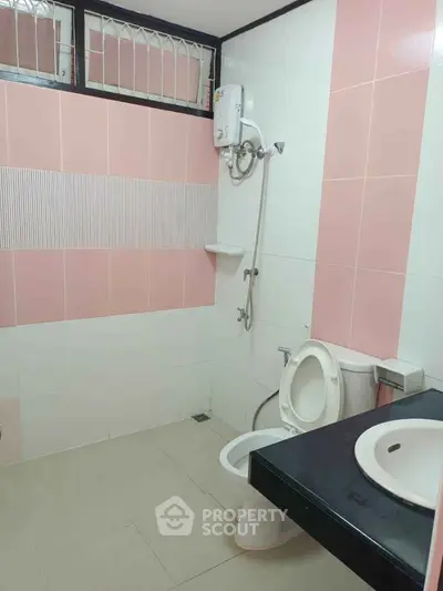 Modern bathroom with pink and white tiles, featuring a shower and toilet.