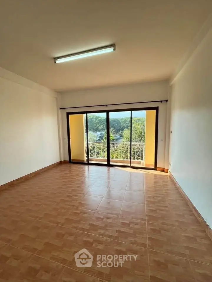 Spacious empty room with large windows and balcony offering scenic views.