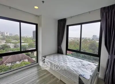 Bright bedroom with large windows offering stunning city views in modern apartment.