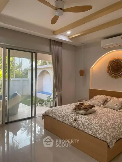 Luxurious bedroom with modern decor and sliding glass doors opening to a serene outdoor space.