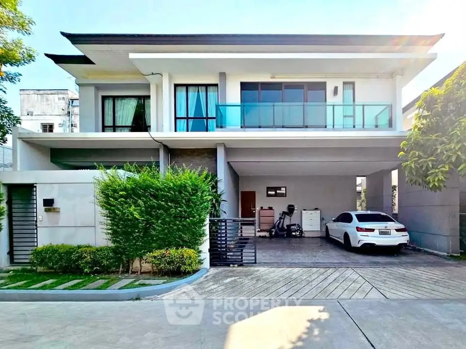 Modern two-story house with spacious driveway and sleek balcony design.