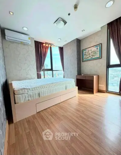 Spacious bedroom with large windows and city view, featuring modern decor and wooden flooring.