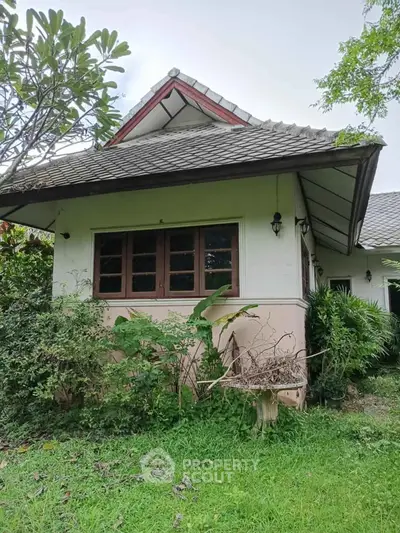 Charming single-story house with lush garden and traditional roof design.