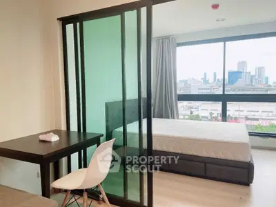 Modern studio apartment with glass partition and city view, featuring a cozy bed and stylish furniture.