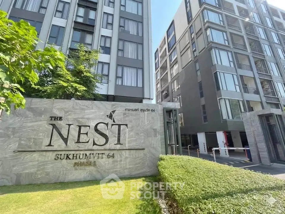Modern condominium exterior at The Nest Sukhumvit 64 with lush greenery and sleek architecture.