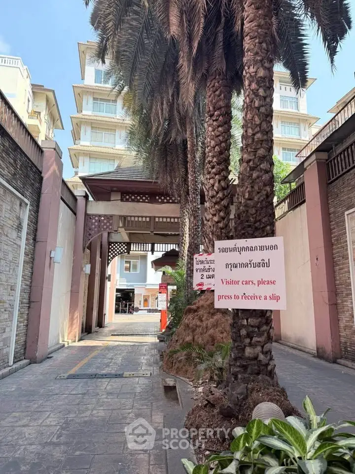 Charming entrance with palm trees leading to a modern residential building.