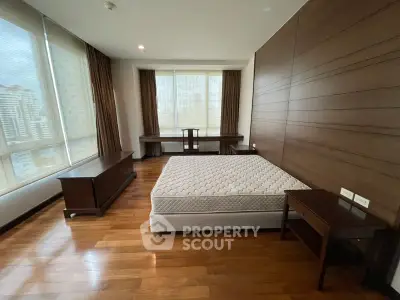 Spacious bedroom with large windows and wooden flooring in modern apartment