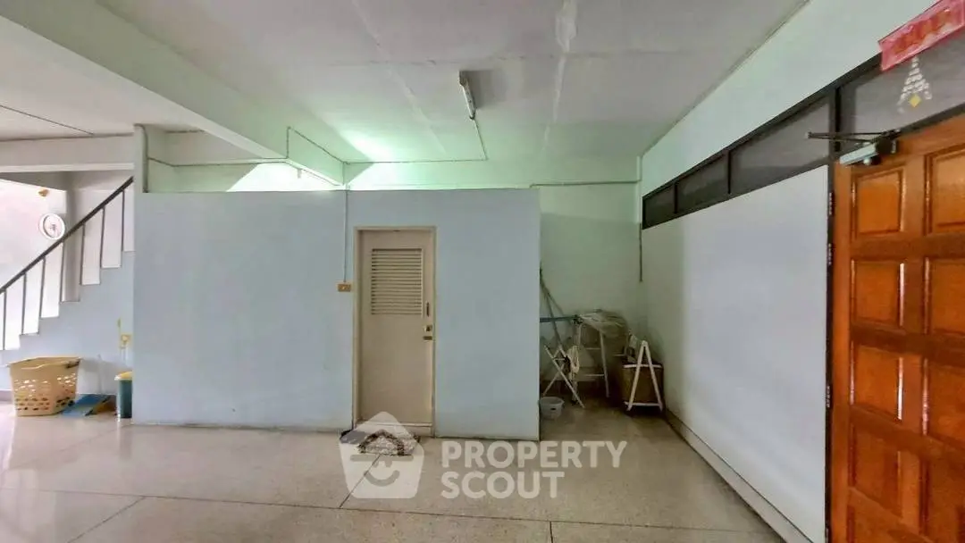 Spacious interior with staircase and wooden door, ideal for versatile use.