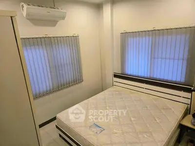 Cozy bedroom with air conditioning and natural light from two windows.